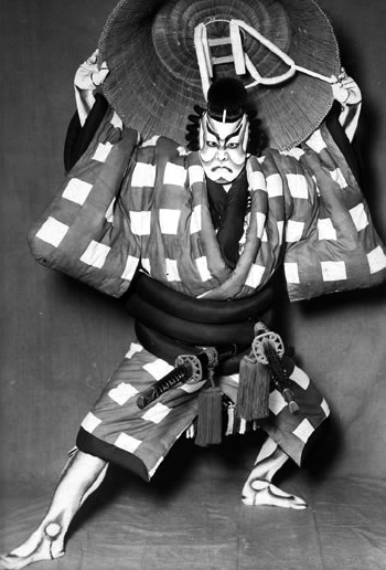 Kabuki actors in elaborate costume and makeup performing on a traditional Japanese stage.
