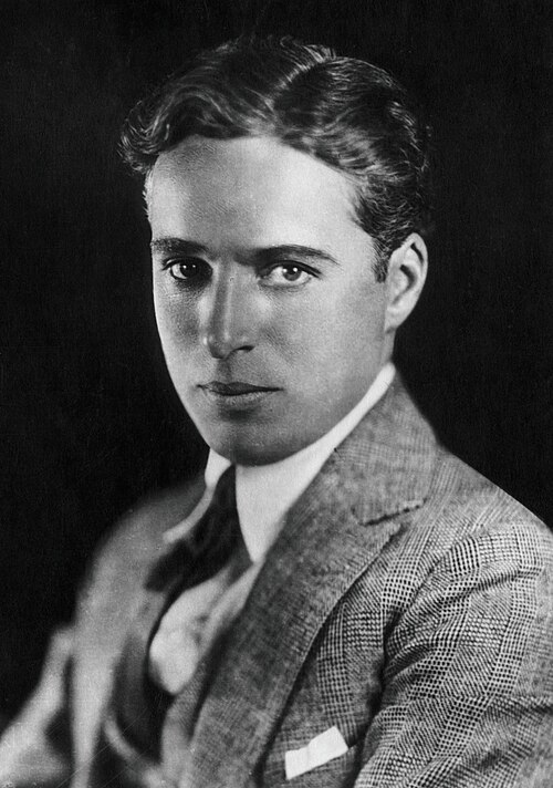 Charlie Chaplin in costume as the Tramp, with bowler hat and cane.