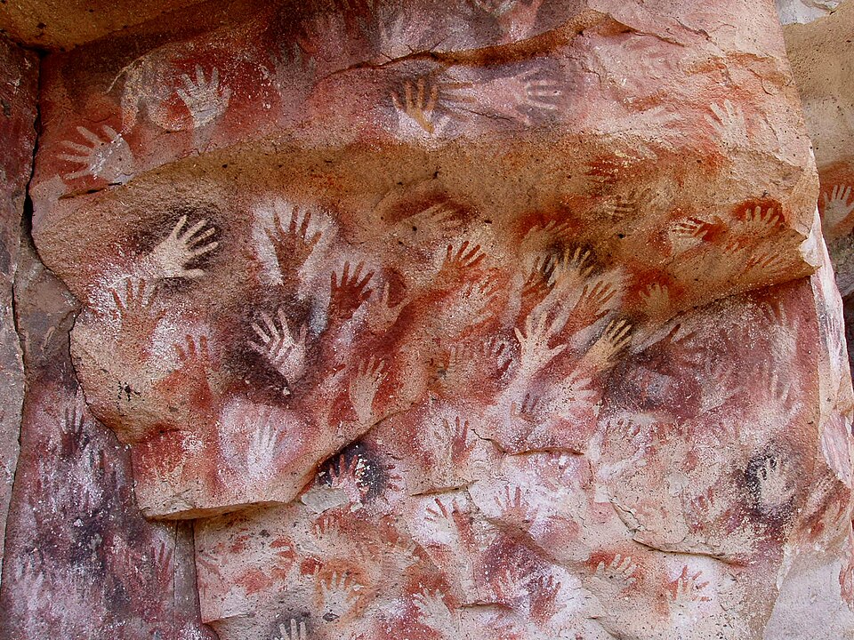 Prehistoric animal paintings in red and black pigment on a cave wall.