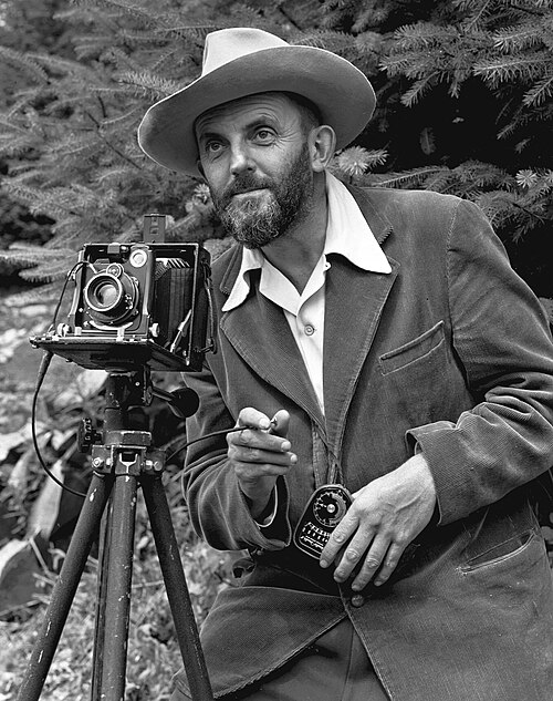 Ansel Adams with a large-format camera on a tripod.