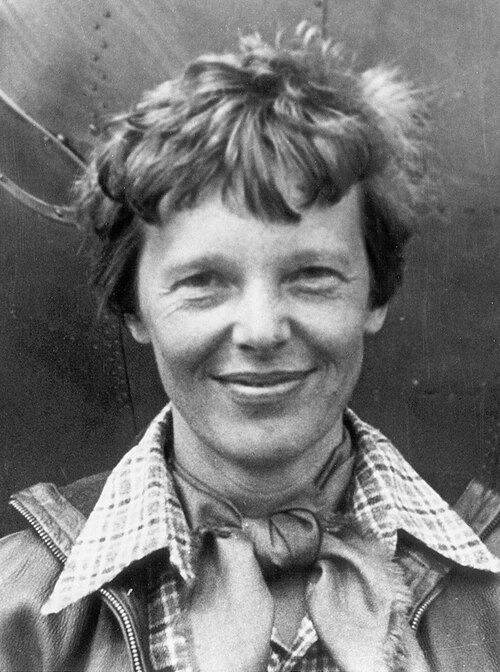 Portrait of Amelia Earhart in flying gear beside an aircraft.